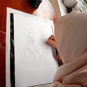 Ibu Nisa drawing out their final design with a pencil