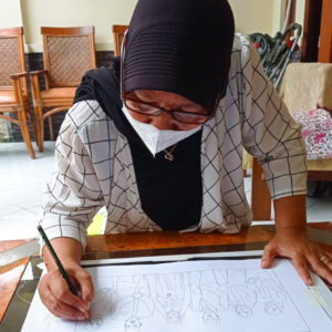 Ibu Dwi Restu drawing out their final design with a pencil