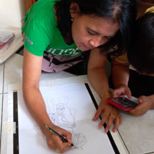 Ibu Yuli drawing out their final design with a pencil