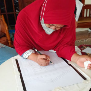 Ibu Munah drawing out their final design with a pencil