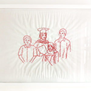 Ibu Suyanah's final framed embroidery of her family. It features four figures standing together. The middle figure has a graduation cap on and is holding a diploma. She looks happy. She is surrounded by a young boy and a young girl and a man.