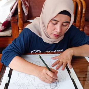 Ibu Mariah drawing out their final design with a pencil