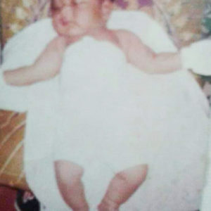 A picture of a baby laying down in a blanket with arms spread wide.