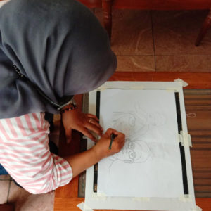 Ibu Diah drawing out their final design with a pencil.
