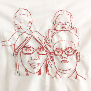 Ibu Diah's final embroidery of her family. There are four faces, a man and a woman both with glasses in front of two babies.