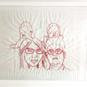 Ibu Diah's final framed embroidery of her family. There are four faces, a man and a woman both with glasses in front of two babies.